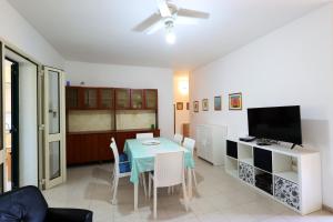 a dining room with a table with chairs and a television at Charming apartment in Torre Pali with large terrace in Torre Pali 