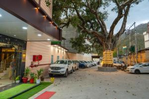 ein Baum vor einem Gebäude mit geparkten Autos in der Unterkunft Hotel The Vaishvik in Katra