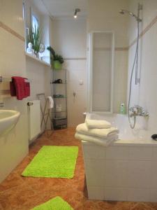 uma casa de banho com uma banheira e um lavatório com esteiras verdes em VILLA FREIA Dresden - Exklusive Ferienwohnung zum Erholen & Entspannen em Dresden