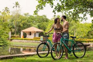 un hombre y una mujer de pie junto a una bicicleta en Eco Pousada Paraíso dos Coqueirais, en Japaratinga