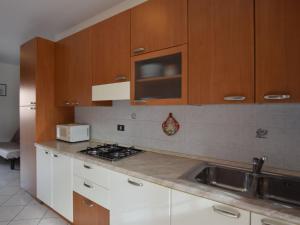 a kitchen with white cabinets and a sink and a microwave at Apartment Acquamarina-2 by Interhome in Rosapineta