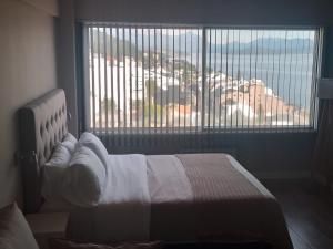 1 dormitorio con cama y ventana grande en Postal del Nahuel en San Carlos de Bariloche