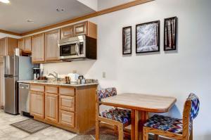 - une cuisine avec des placards en bois, une table et un four micro-ondes dans l'établissement Slopeside 2741, à Keystone