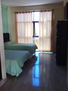 a bedroom with two beds and a large window at Hostal El Paraiso in Tarija