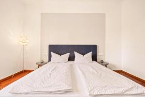 ein großes weißes Bett mit weißer Bettwäsche und Kissen in der Unterkunft Wohnen in der alten Post - 5 min zum Ravensburger Spieleland in Meckenbeuren