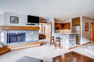 a living room with a fireplace and a kitchen at Lakeside 1491 in Keystone