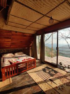 a bedroom with a bed and a large window at Sunset Valley Kerala - Where Every Evening Unveils a Perfect Sunset with Private Waterfalls in Pīrmed