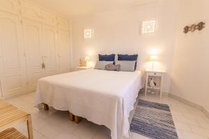 um quarto com uma grande cama branca com almofadas azuis em Azul em Sagres