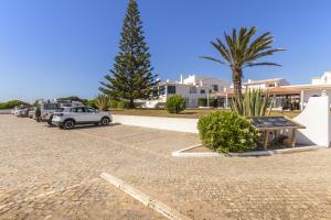 a parking lot with parked cars and a palm tree at Azul in Sagres