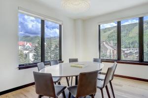 ベールにあるThe Lion Vail- 4 Br Modern Mountain Luxury- 2966 Sq Ft Condoの大きな窓のある客室で、テーブルと椅子が備わります。