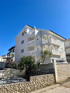 a white apartment building with a stone wall at Apartments Imperium in Trogir