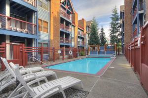 a swimming pool with chaise lounge chairs in front of a building at River Mtn Lodge E304 in Breckenridge
