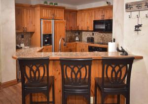une cuisine avec des placards en bois et un îlot avec des tabourets de bar dans l'établissement Elkhorn 509, à Avon