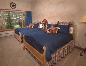 a bedroom with two beds with blue sheets and a window at Elkhorn 509 in Avon
