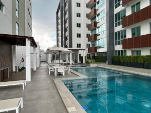 a swimming pool with tables and umbrellas next to a building at New luxury apartment with king - size bed Ceibos in Guayaquil