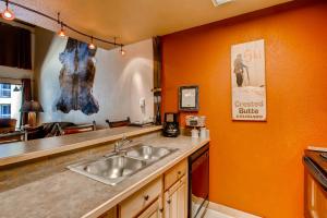 een keuken met een wastafel en een oranje muur bij Tastefully Decorated Emmons Condo Condo in Crested Butte