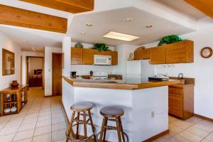 a kitchen with wooden cabinets and bar stools at View Of Mt, Crested Butte And Lifts 2 Br Condo Condo in Crested Butte