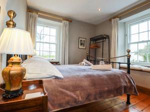 a bedroom with a bed and a lamp on a table at Roskorwell Manor in Helston