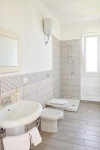 a white bathroom with a sink and a toilet at Salinelle Rooms in Lascari +24 photos