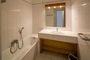 a bathroom with a tub and a sink and a mirror at Hotel Provençal in Hyères