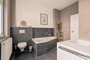 a bathroom with a tub and a toilet and a sink at Wohnen bei der alten Dampflok inkl Balkon - 5 min zum Ravensburger Spieleland in Meckenbeuren +11 photos