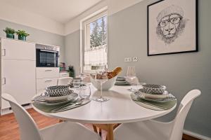 a white dining room with a white table and chairs at Wohnen bei der alten Dampflok inkl Balkon - 5 min zum Ravensburger Spieleland in Meckenbeuren