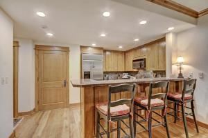 a kitchen with wooden cabinets and a bar with stools at Settler's Lodge 204 in Edwards