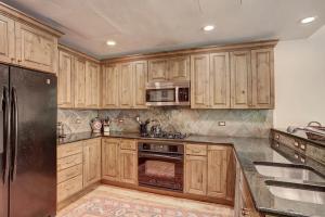 Una cocina con gabinetes de madera y electrodomésticos de acero inoxidable. en Elegant Updated 3 Bedroom Condo At One Arrowhead Place Condo, en Edwards