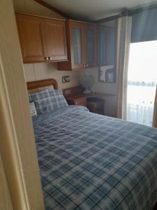 a bedroom with a bed with a blue checked blanket at Millfield caravan site, caravan L6 in Ingoldmells