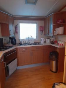 a kitchen with wooden cabinets and a sink and a window at Millfield caravan site, caravan L6 in Ingoldmells