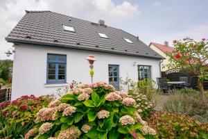 a white house with a flower garden in front of it at Ferienwohnung Fortuna II in Thiessow