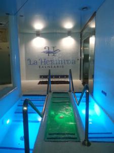 a swimming pool in a building with a sign on the wall at Hotel Balneario La Hermida in La Hermida
