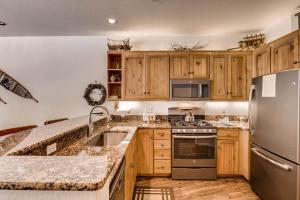 a kitchen with wooden cabinets and a stainless steel refrigerator at Ski Tip Townhomes 8713 in Keystone
