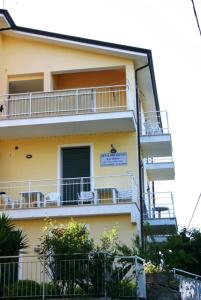 ein gelbes Gebäude mit Balkonen, Tischen und Stühlen in der Unterkunft B&B La Baia Di Fiascherino citr01101sei-BEB-0011 in Tellaro