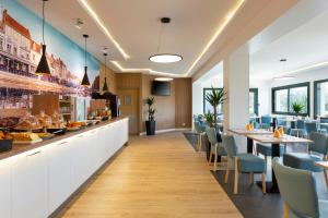 a restaurant with a long counter with chairs and tables at The Originals City, Tabl'Hôtel, Amiens in Longueau