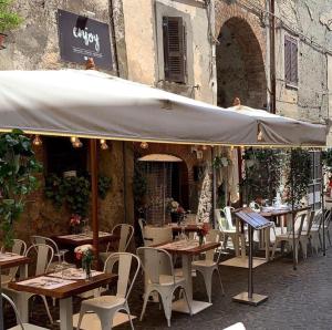 een openluchtrestaurant met tafels en stoelen en een parasol bij Enjoyhousebracciano suite1 in Bracciano