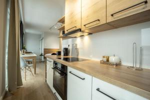 uma cozinha com armários brancos e um balcão de madeira em WiguryTower Apartaments 70' em Lódź