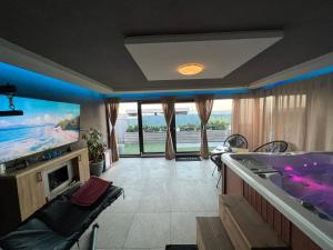 uma sala de estar com uma banheira e uma televisão em Jacuzzi Home em Oradea