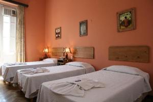 3 camas en una habitación con paredes de color naranja en Plaza Hotel en Salta
