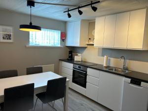 cocina con armarios blancos, mesa y sillas en The Painter's house, en Siglufjörður