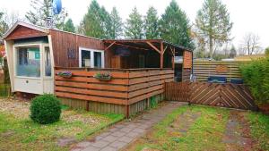 una piccola casa con una recinzione in un cortile di *Little Oak* Super schattige houten chalet met veranda in een bosrijke omgeving. a Eext