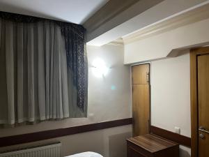 イスタンブールにあるグランド ペニンシュラ ホテルのベッド、カーテン、窓が備わる客室です。