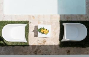 two white chairs and a plate of fruit on the ground at AH Premium Baia dei Faraglioni in Mattinata