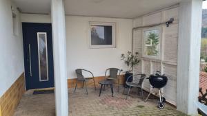 a porch with four chairs and a blue door at Fridolin in Eichenbühl