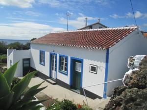 une petite maison blanche avec des portes bleues dans l'établissement Quintinha da Chinela, à Porto Judeu