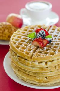 a stack of waffles with strawberries on top on a plate at Courtyard by Marriott Paramaribo in Paramaribo