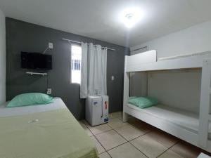 um quarto com 2 beliches e uma televisão em Casa Aeroporto Pousada no Recife