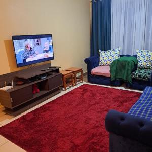 - un salon avec une télévision à écran plat et un tapis rouge dans l'établissement Shiks Apartment retreat, à Nairobi