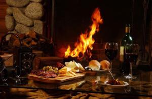 a table with food and wine glasses and a fireplace at Cabañas Rincon del Lago in Villa La Angostura