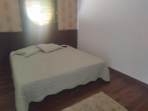 um quarto com uma cama com lençóis brancos e uma janela em Kitnet na Rua Sapucai em Belo Horizonte
